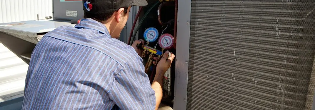 HVAC technician servicing a condenser unit in Fort Lupton