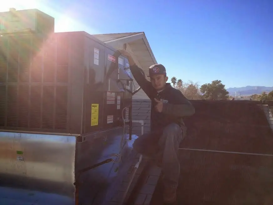 HVAC technician performing AC Tune-Up on a rooftop unit in Fort Lupton